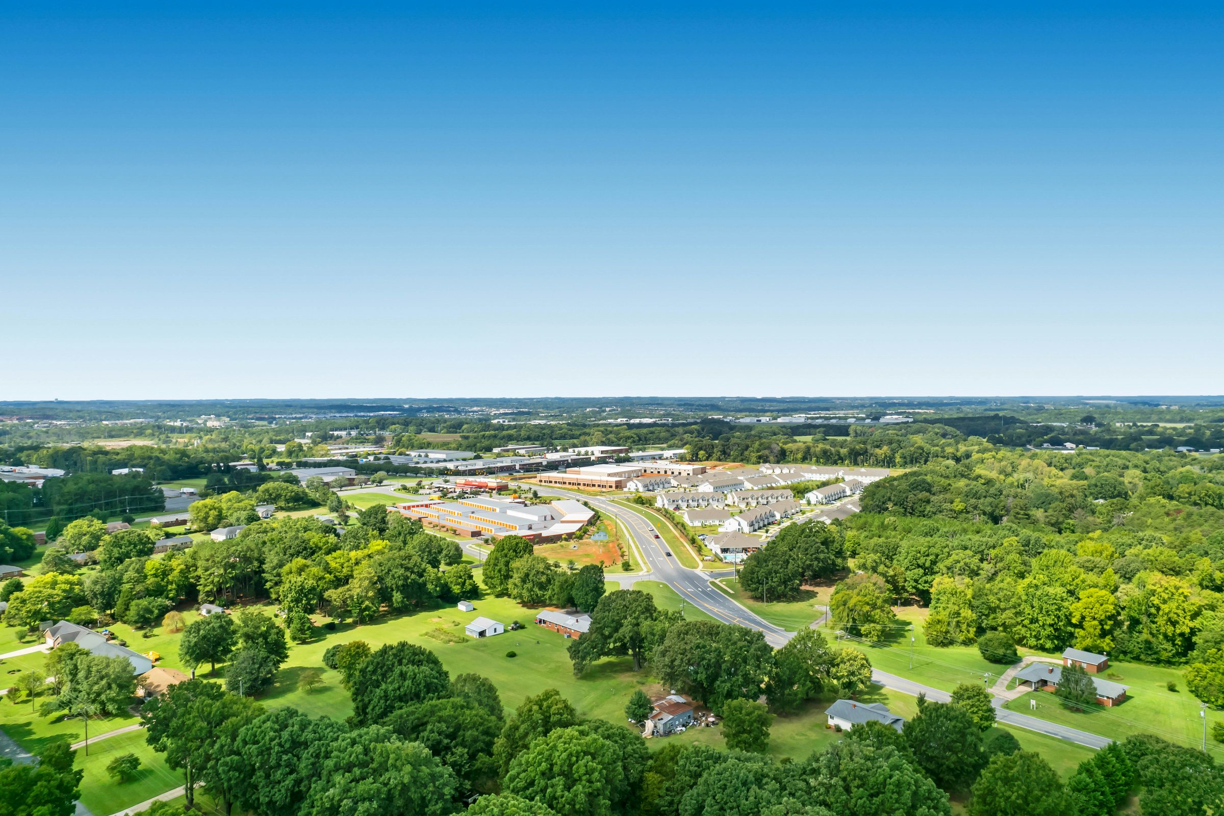 Green countryside and a small town under a blue sky, seen from the air
